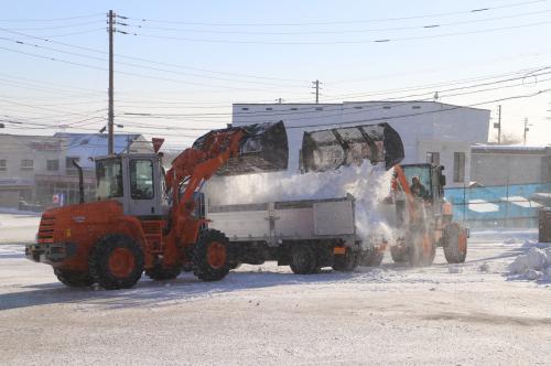 ショベルが雪をトラックに積む